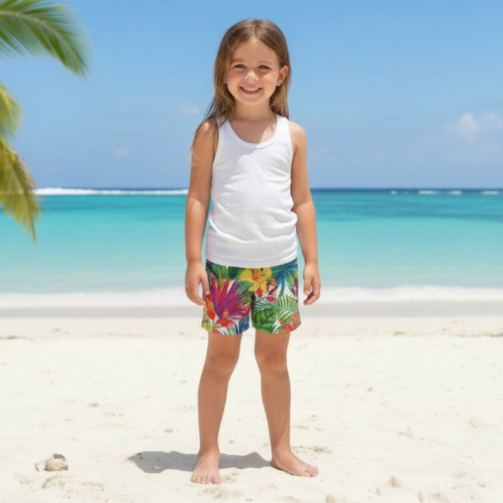 Child wearing colorful Kids Hawaiian Tropical Board Shorts with a white tank top on a beach.
