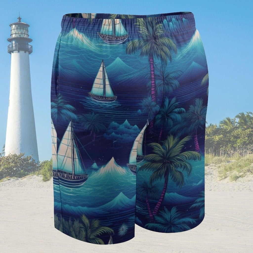 Beach shorts with tropical design featuring sailboats and palm trees on a sandy beach with a lighthouse in the background.
