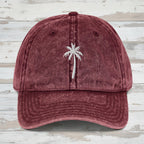 Maroon cap with a white palm tree embroidery on a rustic wood background