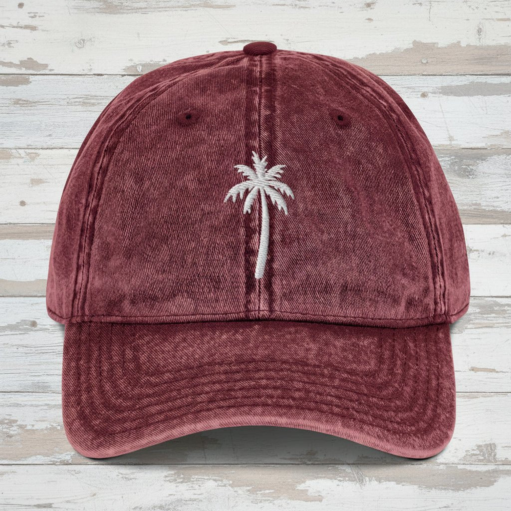 Maroon cap with a white palm tree embroidery on a rustic wood background