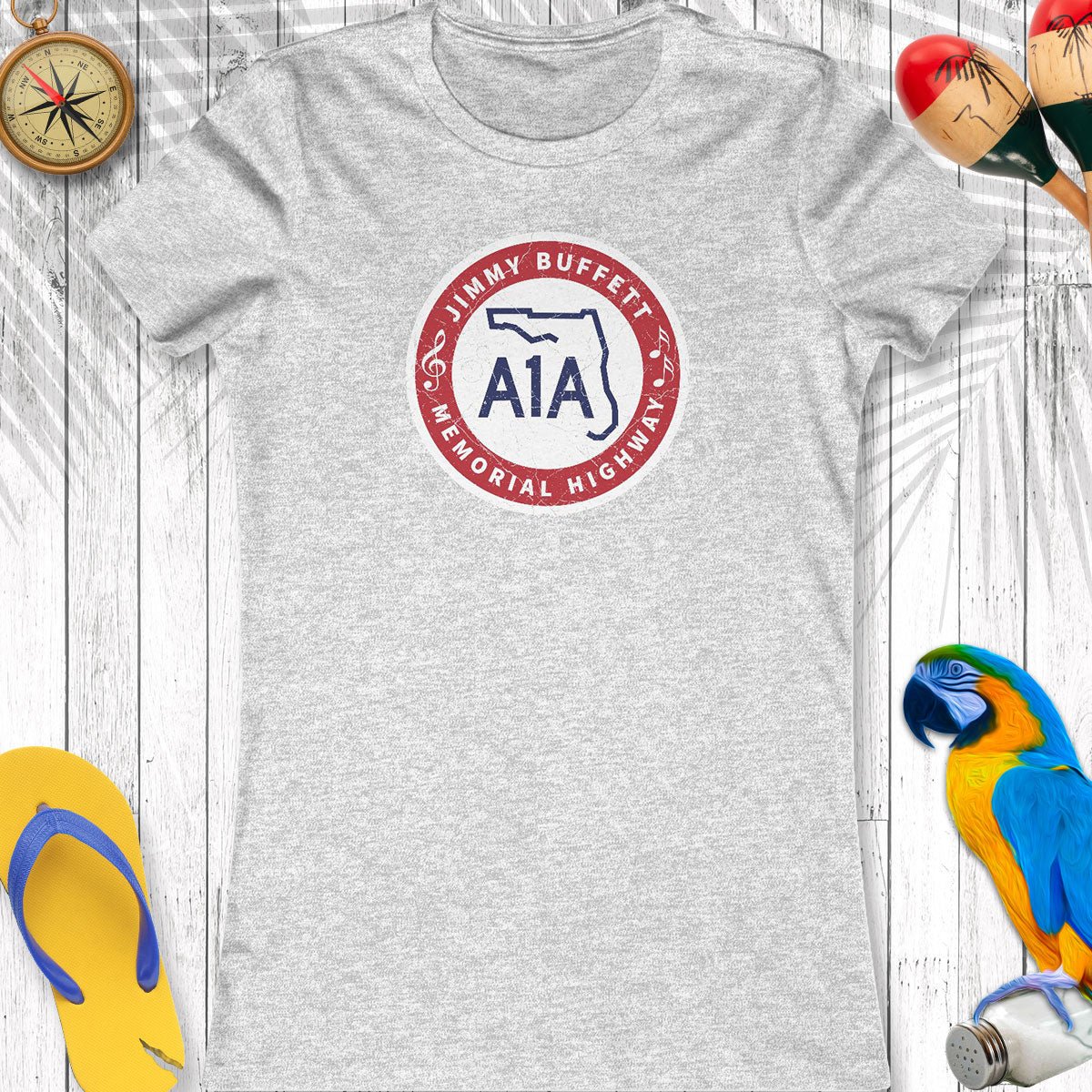 Gray t-shirt with a logo on a wooden surface with beach accessories.