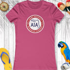 Pink t-shirt with a logo on a wooden surface with decorative items around