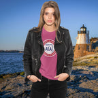 Person wearing a black leather jacket and pink shirt with a lighthouse and body of water in the background