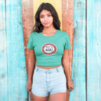 Woman wearing a green t-shirt with a logo against a wooden background