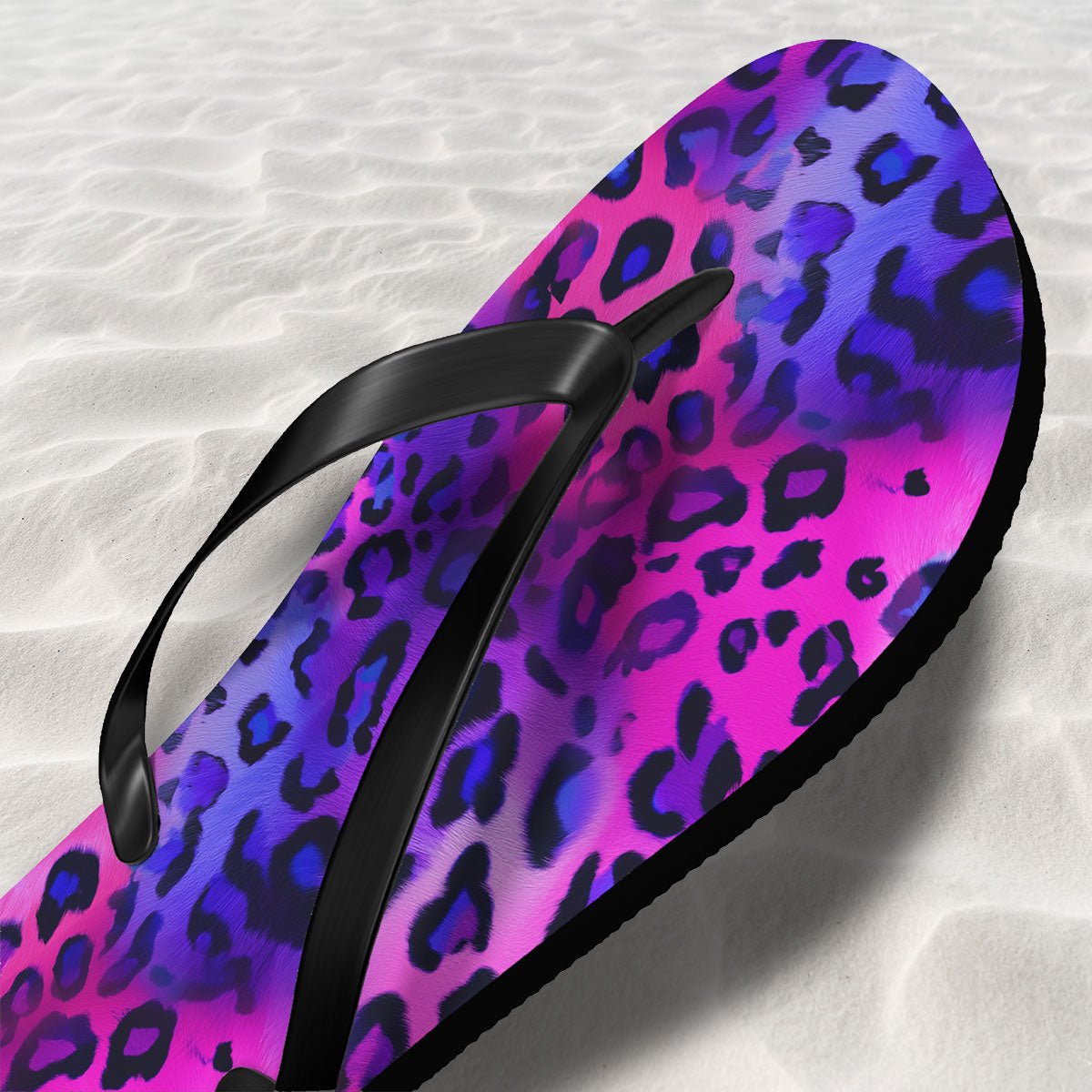 Flip-flop with purple and pink leopard print on a sand textured background