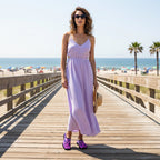 A person standing on a sandy beach boardwalk wearing slip-on water shoes with a bright pink and purple leopard print and black trim.