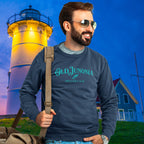 Man wearing a sweatshirt with 'Old Junonia' text in front of a lighthouse at night.