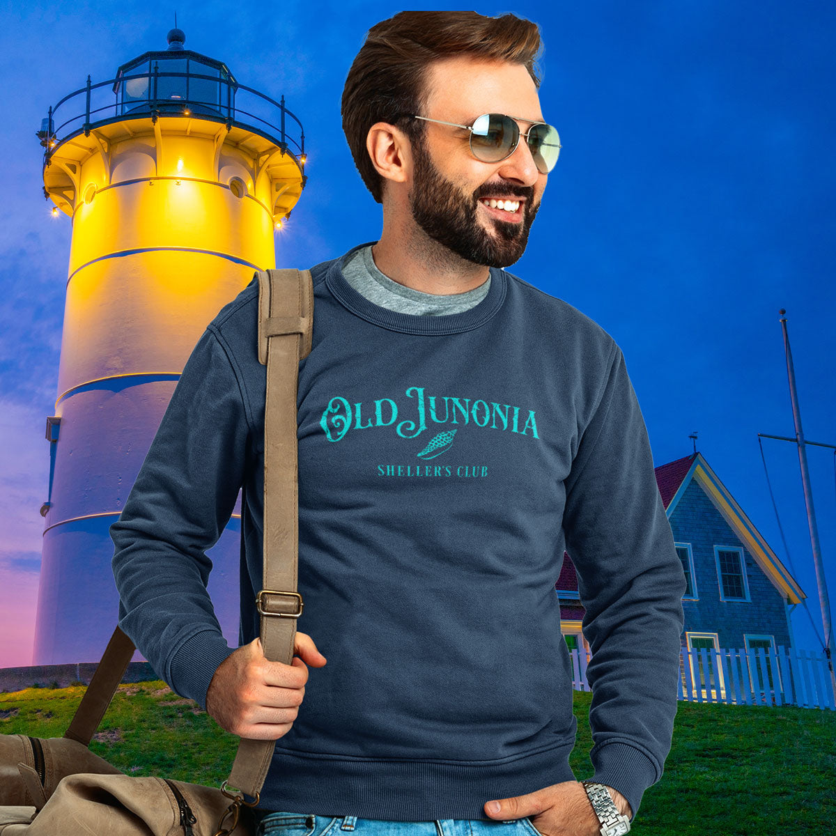 Man wearing a sweatshirt with 'Old Junonia' text in front of a lighthouse at night.
