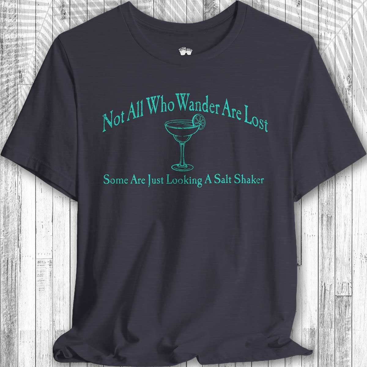 Navy blue Parrot Head Adventure Shirt with green text and a martini glass graphic on a wooden surface