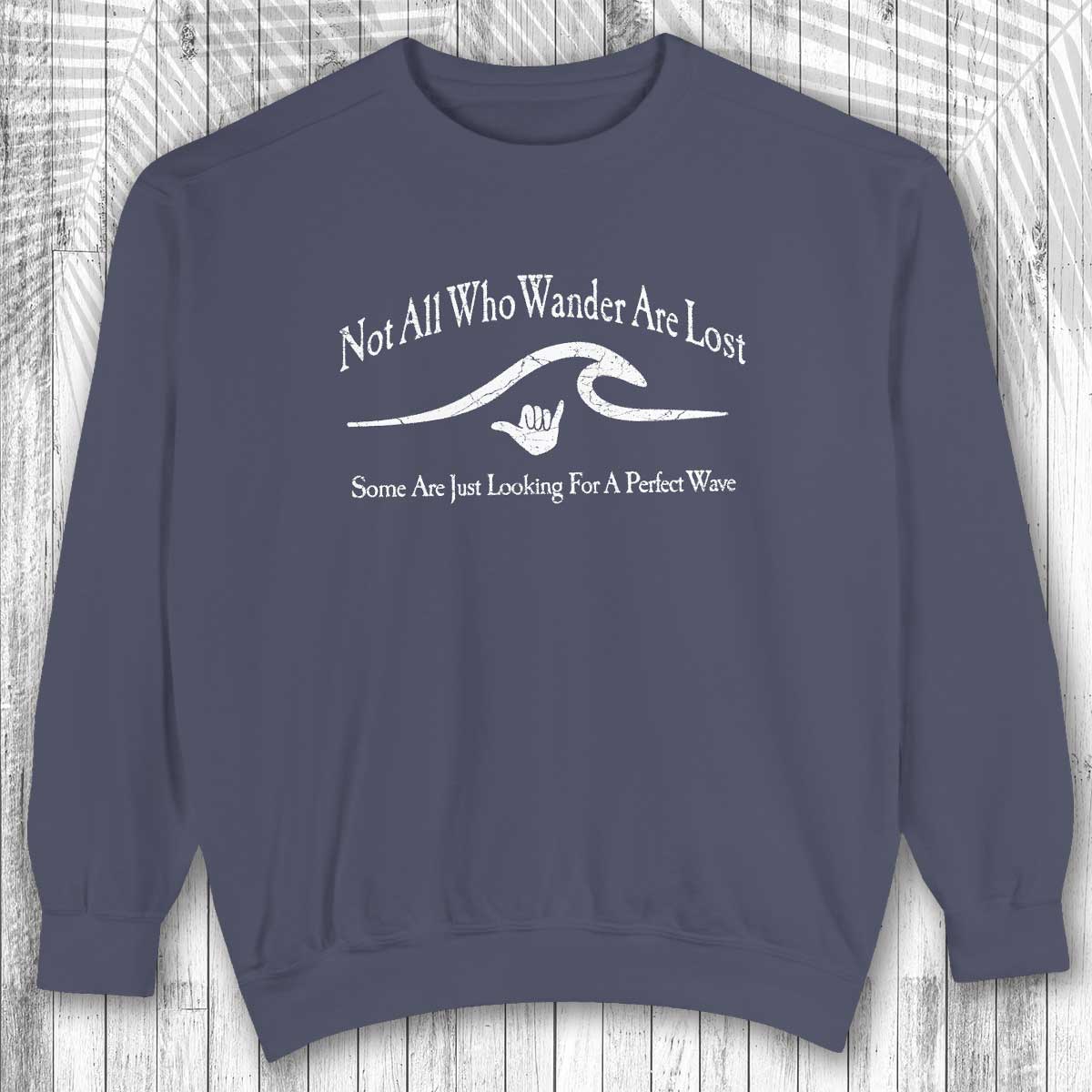 Navy blue shaka inspired sweatshirt with white text and graphic on a wooden background