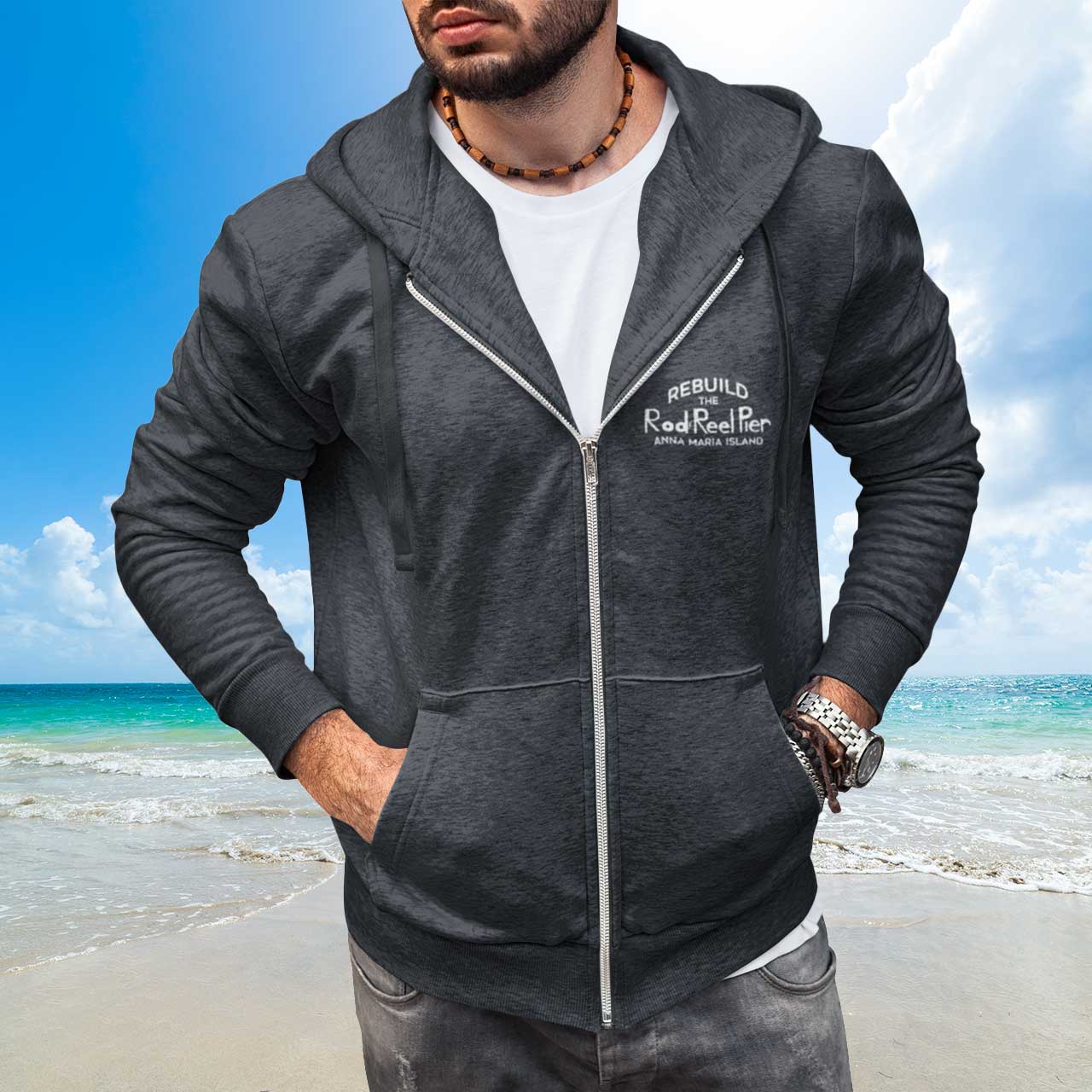Man wearing a gray hoodie with branding on a beach