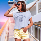 Woman wearing a light blue t-shirt with text and graphics, standing on a cruise ship deck.