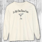 long-sleeve Ivory shirt with a graphic and text It's My Own Damn Fault on a wooden surface