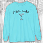 Light blue long-sleeve shirt with a graphic and text on a wooden background
