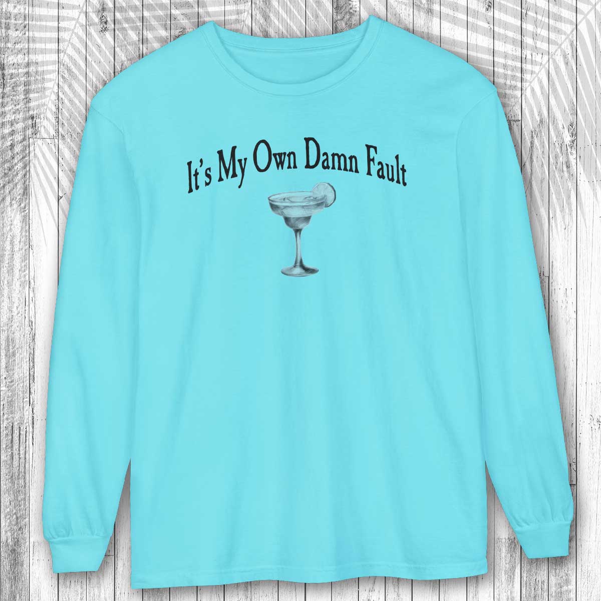Light blue long-sleeve shirt with a graphic and text on a wooden background
