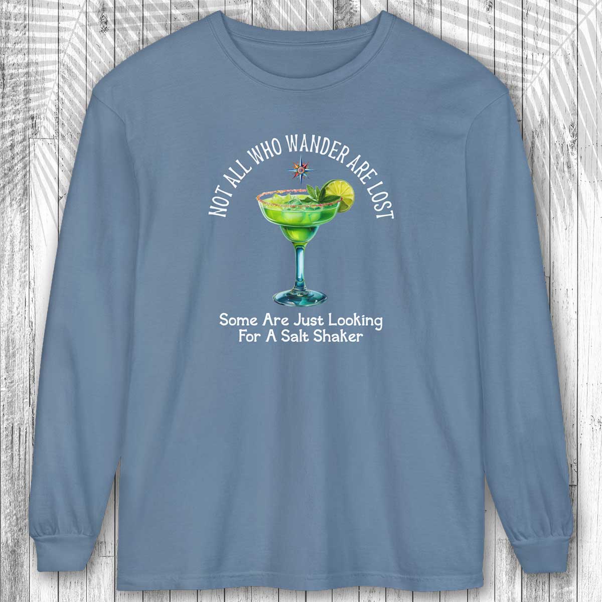 Blue long-sleeve shirt with a graphic of a margarita and text on a wooden background