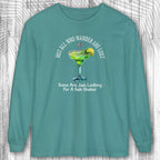 Teal long-sleeve shirt with a graphic of a margarita and text: Not All Who Wander Are Lost - on a wooden background