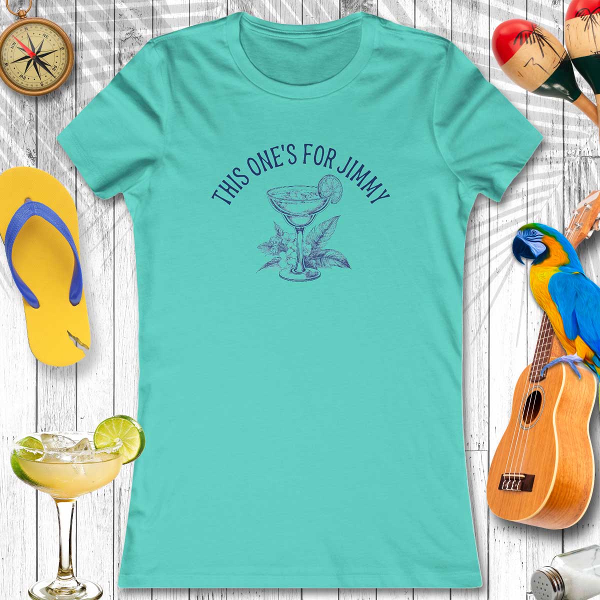 Teal t-shirt with a graphic and text, surrounded by party items on a wooden surface