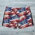 American flag patterned swim shorts on a rustic wood surface.