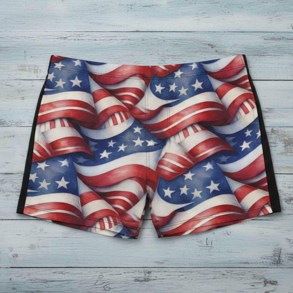 American flag patterned swim shorts on a rustic wood surface.