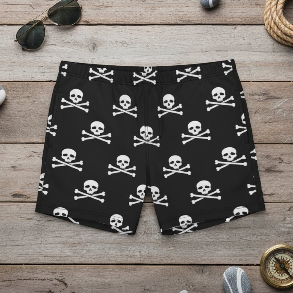 Black swim shorts with white skull and crossbones pattern on a nautical wood background