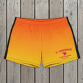 Orange and yellow swim shorts with 'St. Somewhere' branding on a beach.
