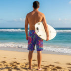 surfer wearing Colorful patterned shorts holding a surfboard looking out over the waves in Waikiki