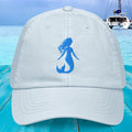 White cap with blue mermaid silhouette on a blue wooden surface with a boat in the background