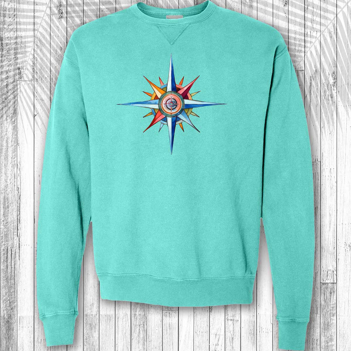 Turquoise sweatshirt with a colorful nautical compass design on a wooden background