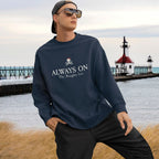 Person wearing a navy sweatshirt with text by a lighthouse and pier.