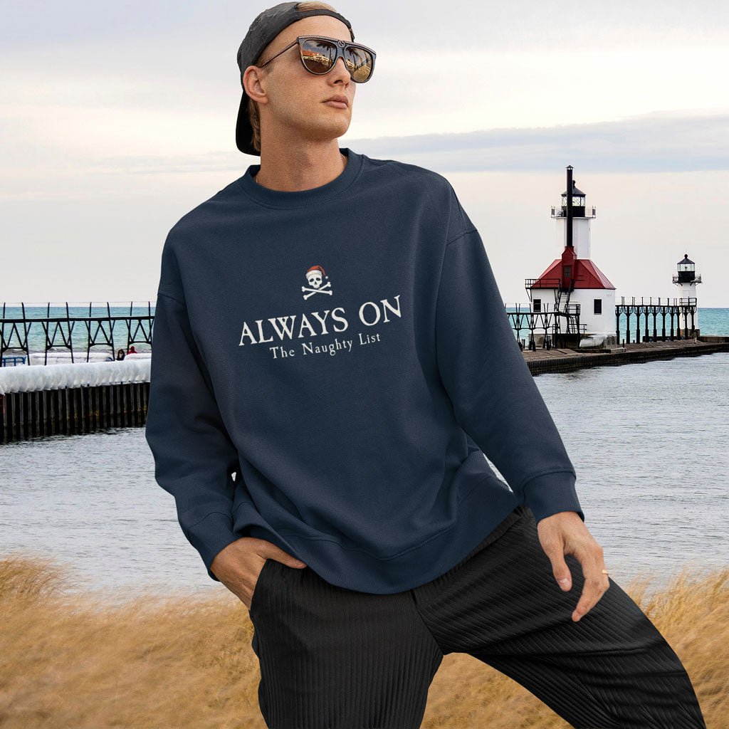 Person wearing a navy sweatshirt with text by a lighthouse and pier.
