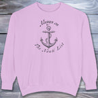 Pink sweatshirt with anchor design and text on a wooden surface