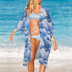 Woman in a blue and white patterned cover-up and bikini standing on a beach.