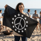 girl holding a black flag with white peace symbol and stars on a beach.