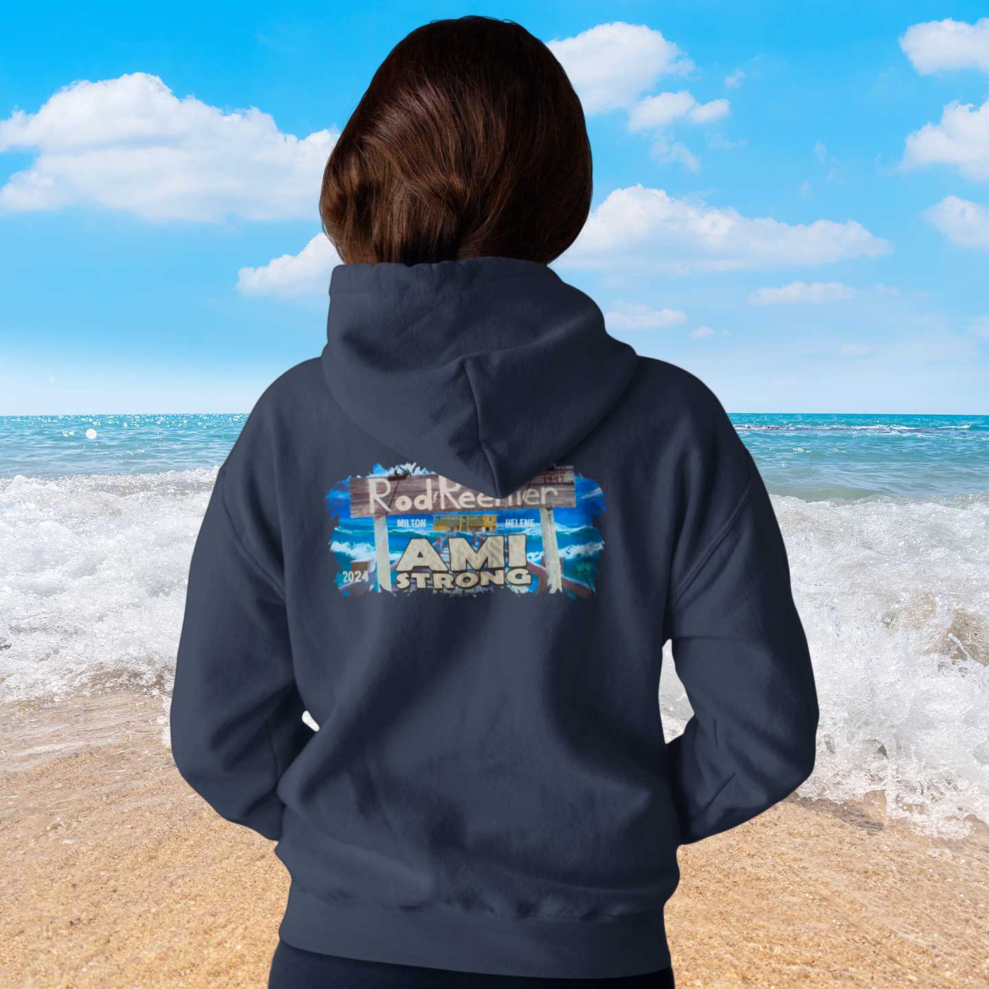 Person wearing a hoodie with 'Ami Strong' text on the beach