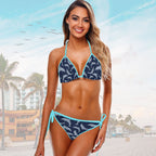 Woman wearing a blue and navy dolphin patterned bikini with a beach background