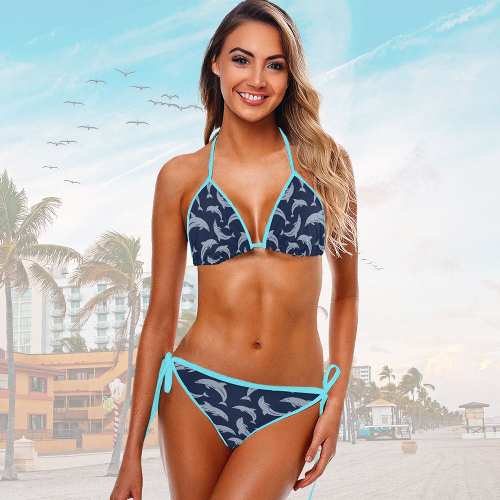 Woman wearing a blue and navy dolphin patterned bikini with a beach background