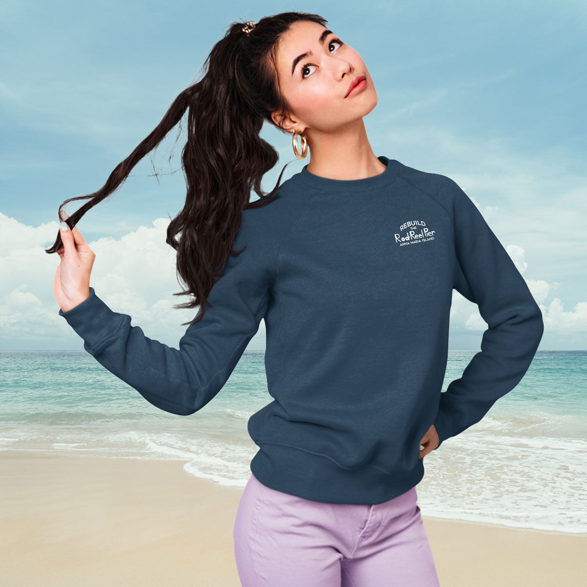Woman wearing a blue sweatshirt with a logo on a beach