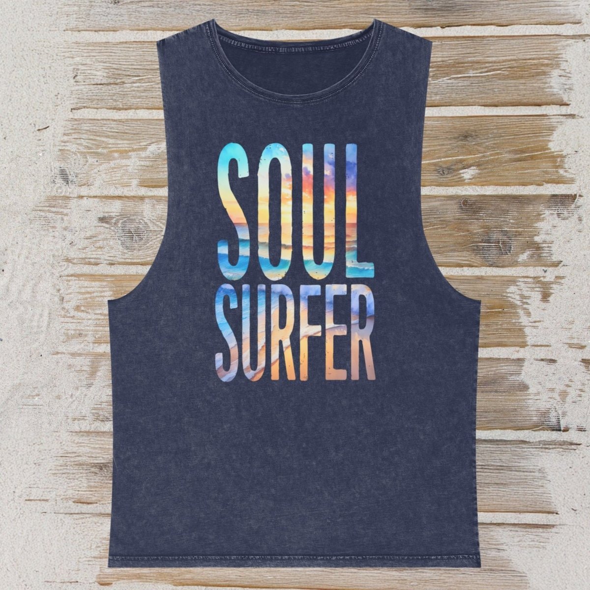 A sleeveless dark navy tank top with 'SOUL SURFER' printed in a colorful gradient wave pattern, laid flat on a rustic wooden plank background.