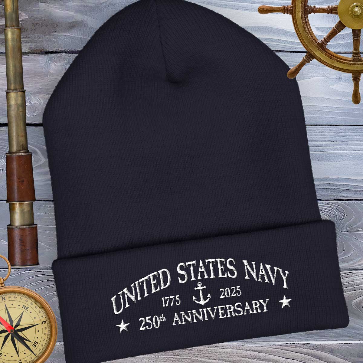 Black beanie with 'United States Navy 250th Anniversary' text on a wooden background with ship wheel and compass.