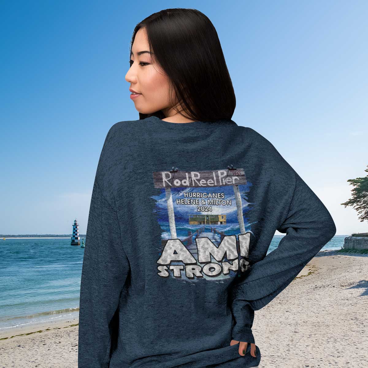 Person wearing a blue sweatshirt with 'Ami Strong' text and graphic on a beach