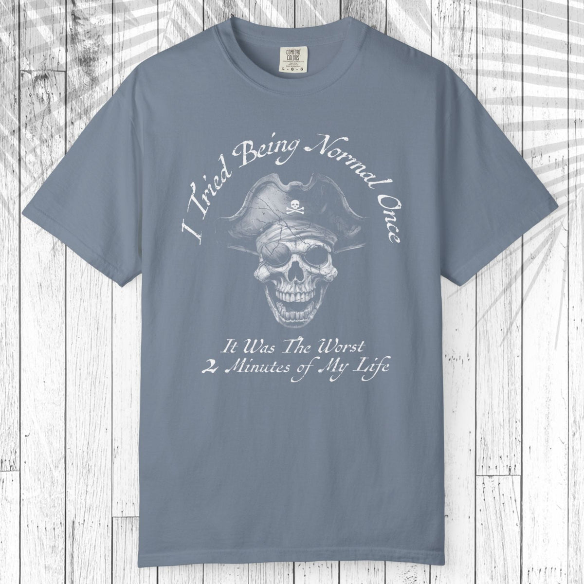 A slate blue short-sleeve t-shirt with a white graphic of a pirate skull and the text 'I Tried Being Normal Once. It Was The Worst 2 Minutes of My Life.