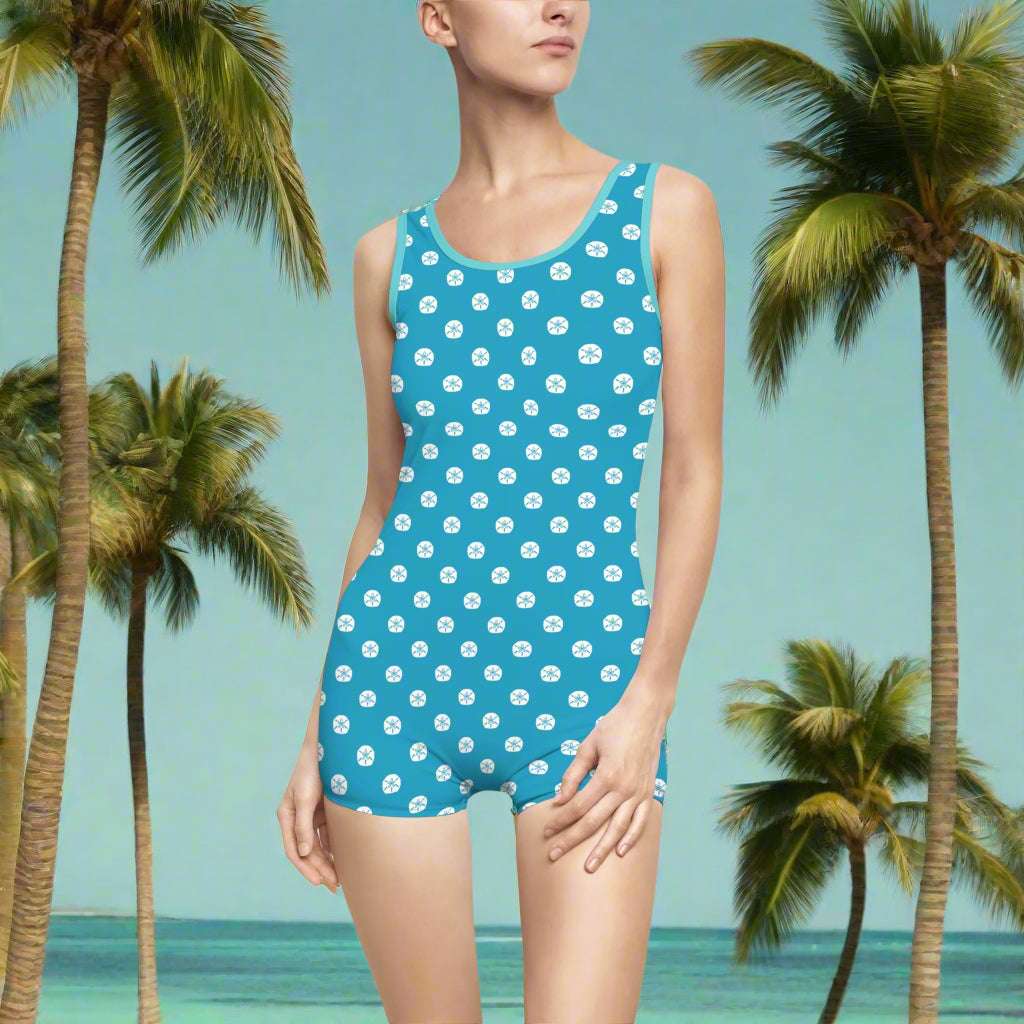 Model wearing vintage one-piece bathing suit with sand dollars for polka dots standing in an island paradise looking for shells