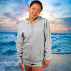 Person wearing a gray hoodie with a beach and ocean background