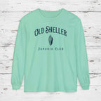 Mint green long-sleeve shirt with 'Old Sheller Junonia Club' text and logo on a wooden surface.