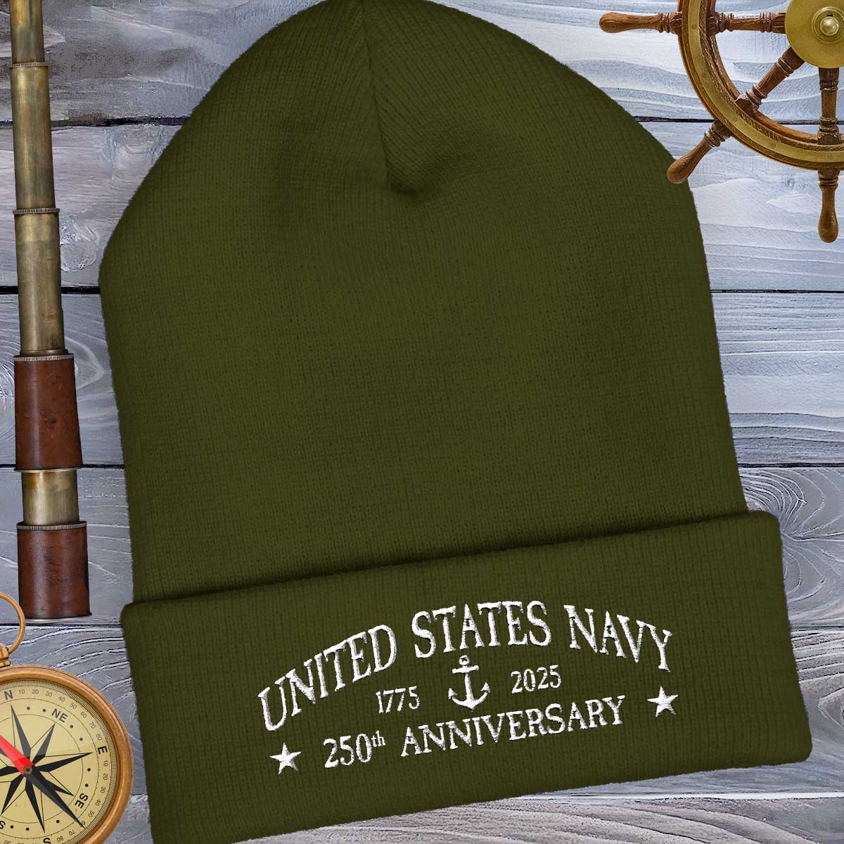 Green beanie with 'United States Navy 250th Anniversary' text on a wooden background with nautical items.