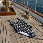 Black swimsuit with white skull and crossbones pattern on the deck of a vintage sailboat