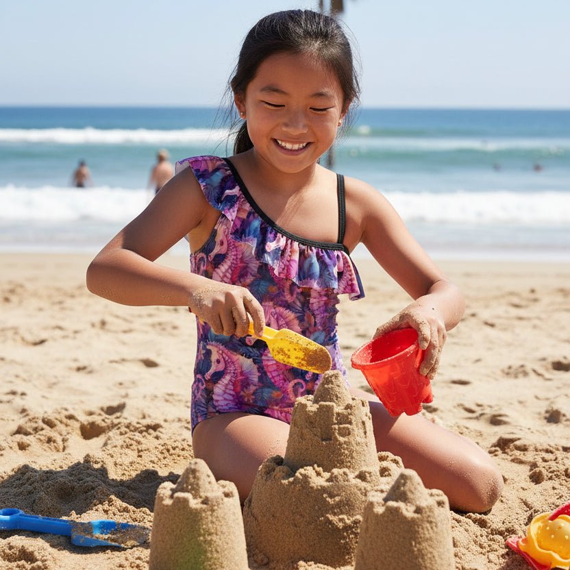 Girl wearing One-piece swimsuit with seahorse pattern playing in the sand in San Diego 