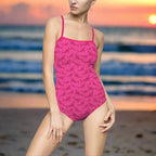 Woman in Hot Pink One Piece Bathing suit with sutel shark pattern is standing on the beach
