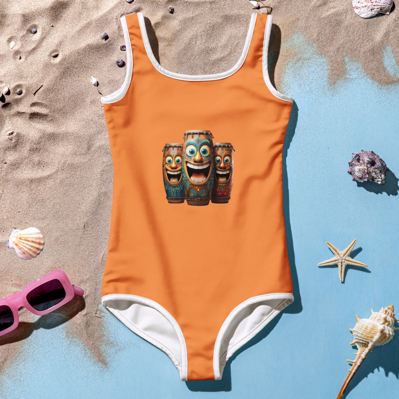Girl's One Piece Orange Swimsuit with Fun Laughing Tiki Bongo Drums on front Lying in the sand among seashells 